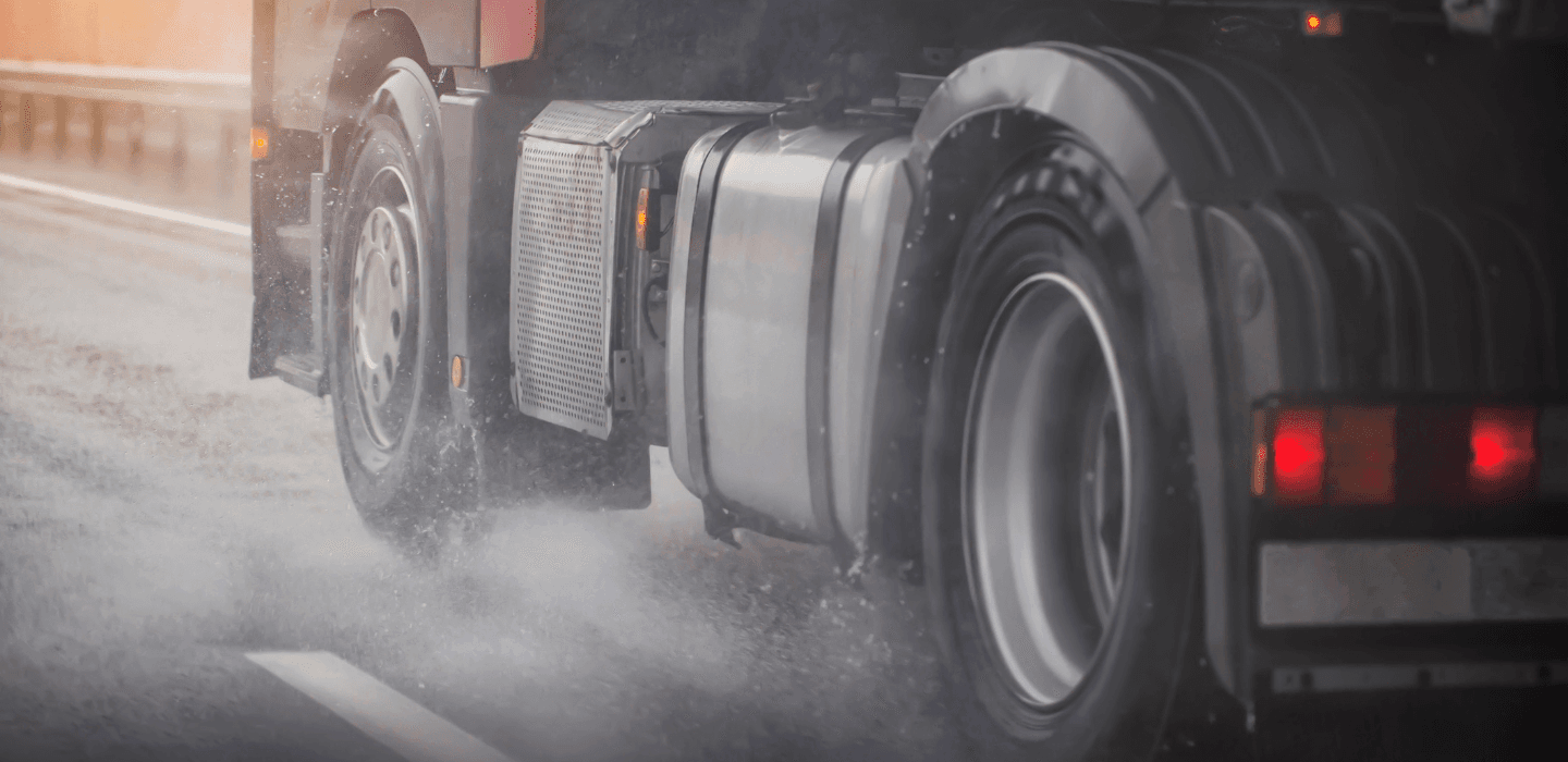 Tył ciągnika siodłowego jadącego po mokrej autostradzie – opony ciężarowe odprowadzające wodę spod kół.