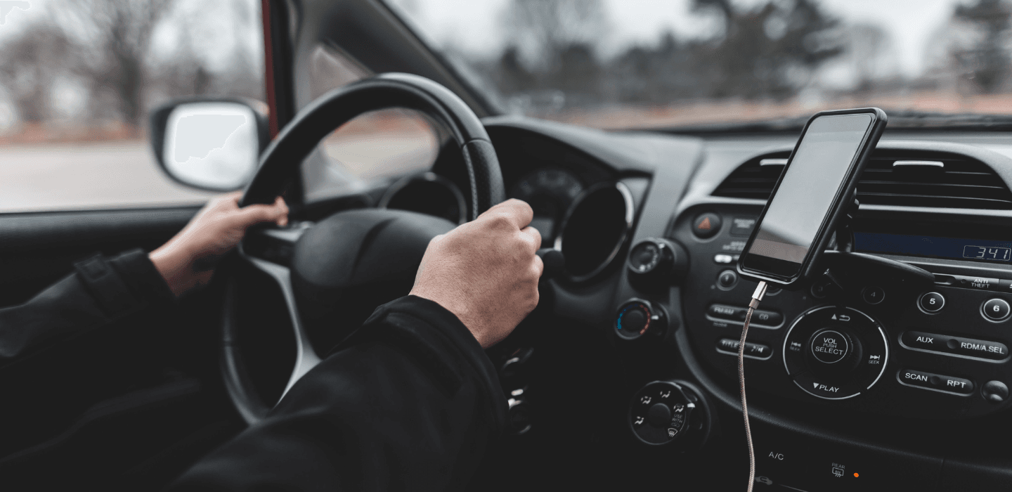 Widok z perspektywy kierowcy na kokpit samochodu i telefon z nawigacją – bezpieczeństwo i komfort prowadzenia na nowych oponach.