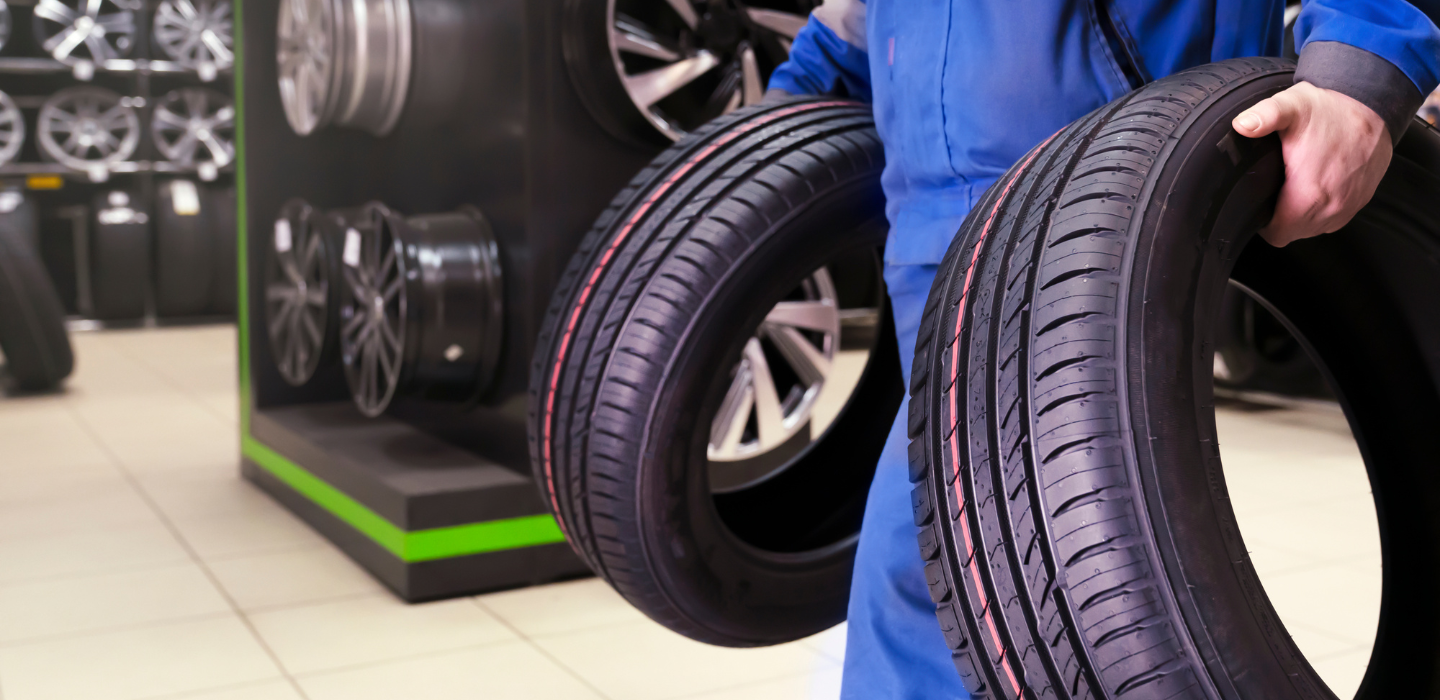 zdjęcie mechanika niosącego nowe opony samochodowe